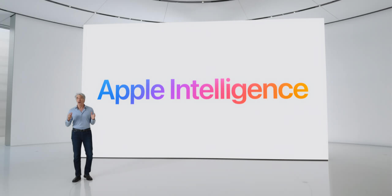 A screenshot of Apple's WWDC24 keynote, featuring Craig Federighi standing in front of a large white screen displaying the words "Apple Intelligence" in colorful gradient letters