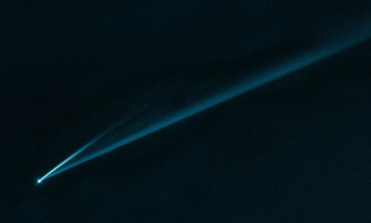 A bright, teal-blue comet streaking across a dark expanse of space